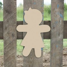 a paper cutout of a teddy bear on a wooden fence with grass in the background