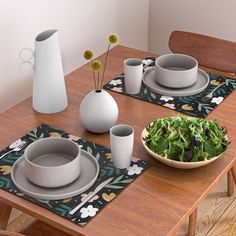 a wooden table topped with plates and bowls filled with green salad next to white vases