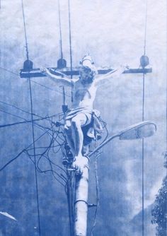 a black and white photo of a crucifix with wires in the background