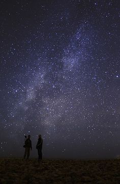 two people are standing under the stars in the sky