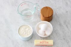 ingredients to make cake sitting on top of a marble counter next to a measuring cup