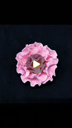 a pink flower sitting on top of a black surface