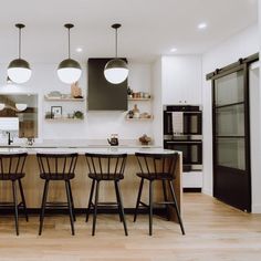 a kitchen with three bar stools next to an island