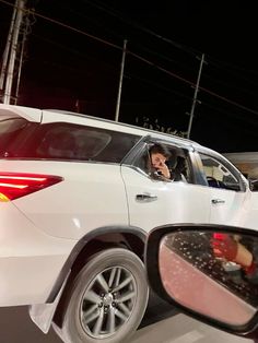 a man is sitting in the driver's seat of a white car at night