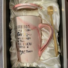 a pink and white coffee mug in a gift box with a spoon, fork and napkin