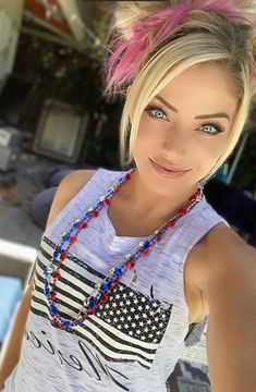 a young woman with pink hair and blue eyes wearing a necklace that has an american flag on it