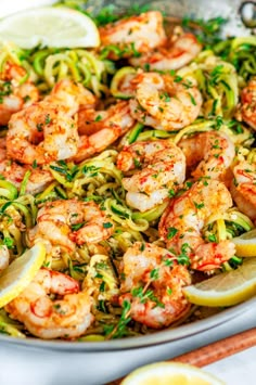 shrimp and zucchini pasta with lemon wedges in a skillet, ready to be eaten