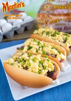 three hot dogs with toppings are on a plate next to eggs and mayonnaise