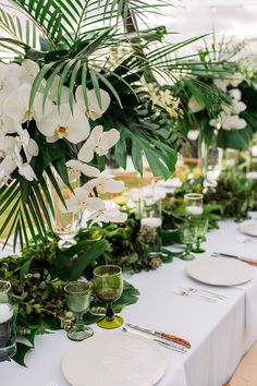 the table is set with white flowers and greenery