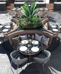 an outdoor seating area with round tables and chairs, surrounded by potted greenery