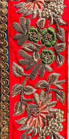 an embroidered red cloth with gold and green flowers on it