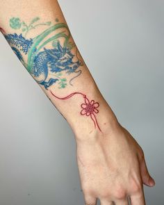 a person's arm with a dragon tattoo on it and a string attached to the wrist