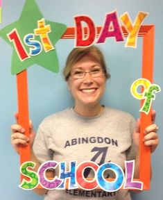 a woman holding up a sign that says 1st day of school