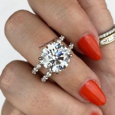 a woman's hand with an orange manicured nail polish and a diamond ring