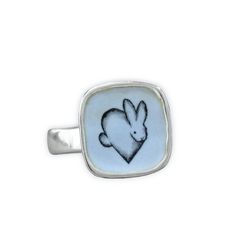 This adorable Rabbit ring will bring you joy every time you wear it. I carved the sterling silver ring setting from a block of wax, then cast that wax ring into metal and molded it so I can make multiples. This ring setting then gets a layer of vitreous enamel (fine glass) and fired at 1400 in a kiln four separate times to build strength and color saturation . Finally I take an illustration from my sketchbook, turn it into an enamel  screen print, and fire that on the top for a durable, waterpro Rabbit Ring, Bunny Jewelry, Wax Ring, Vitreous Enamel, Sterling Silver Rings Set, Build Strength, Silver Ring Set, Dog Jewelry, My Sketchbook