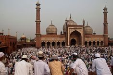 several men standing in front of a large building with many minages on it's sides