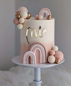 a pink and gold birthday cake on a white plate with the word mia spelled in cursive letters