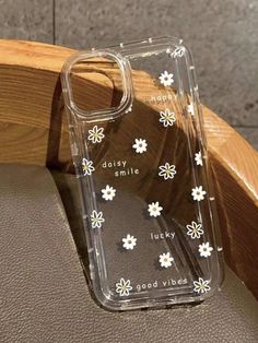 a clear case with white flowers on it sitting on a wooden chair next to a wall