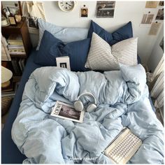 a bed covered in blue sheets and pillows with headphones on top of the covers