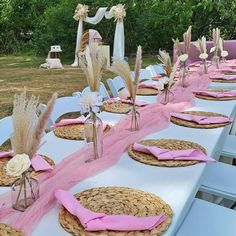 a table set up for a wedding with pink napkins and place settings on it