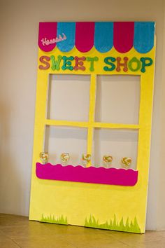 a yellow and pink candy shop display on the floor in front of a white wall