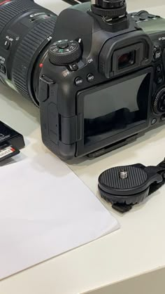 a camera sitting on top of a white table next to a cell phone and pen