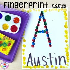 a child's name is painted on a piece of paper next to a painting tray