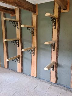 several shelves made out of wood and wrought iron brackets are lined up against the wall