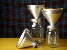 three glass jars with lids and silver funnels