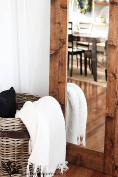 a mirror sitting on top of a wooden floor next to a basket filled with pillows