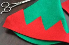 a pair of scissors sitting on top of a piece of felt next to a red and green christmas tree