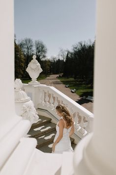 a woman in a wedding dress walking down some stairs