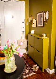 a vase filled with pink flowers sitting on top of a wooden table next to a door