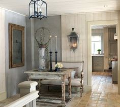 a dining room table and chairs in front of a light fixture with two candles on it