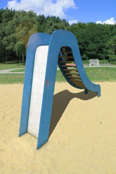 a blue and white playground slide in the sand