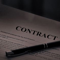 a pen sitting on top of a paper with the word contract written in it's center