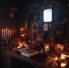 a table with candles and pictures on the wall in a room that has dark walls