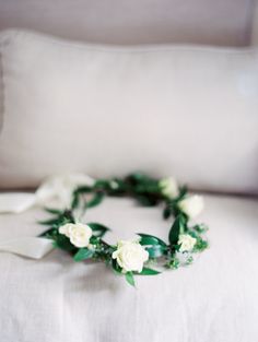 a white rose and green leaf wreath on a chair with a pillow in the background