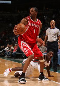 a basketball player dribbles the ball while being guarded by an opposing team member