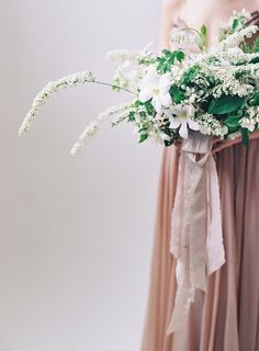 a woman holding a bouquet of white flowers in her hand on the instagram page