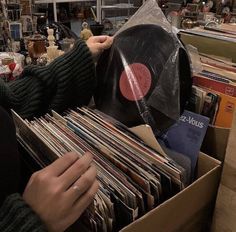 a person holding a record in a box filled with records