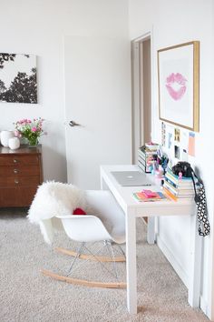 a white desk and chair in a room with pictures on the wall above it,