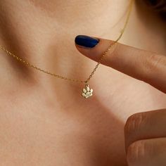 a woman's hand with a tiny gold necklace on her left shoulder and a blue manicured nail