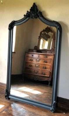 a large mirror sitting on top of a wooden floor next to a dresser and chair