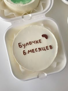 two cakes in plastic containers with writing on them