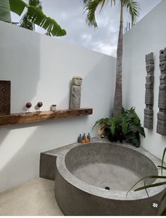 a bath tub sitting under a palm tree next to a white wall