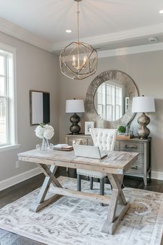 a dining room table with a laptop on top of it next to a lamp and mirror