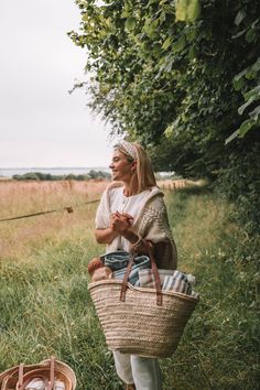 a woman holding a wicker basket in the grass