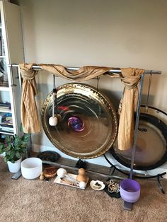 a large gong sitting on top of a metal stand next to other musical instruments and pots