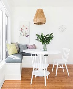 a white table and chairs in a room with wood flooring next to a window